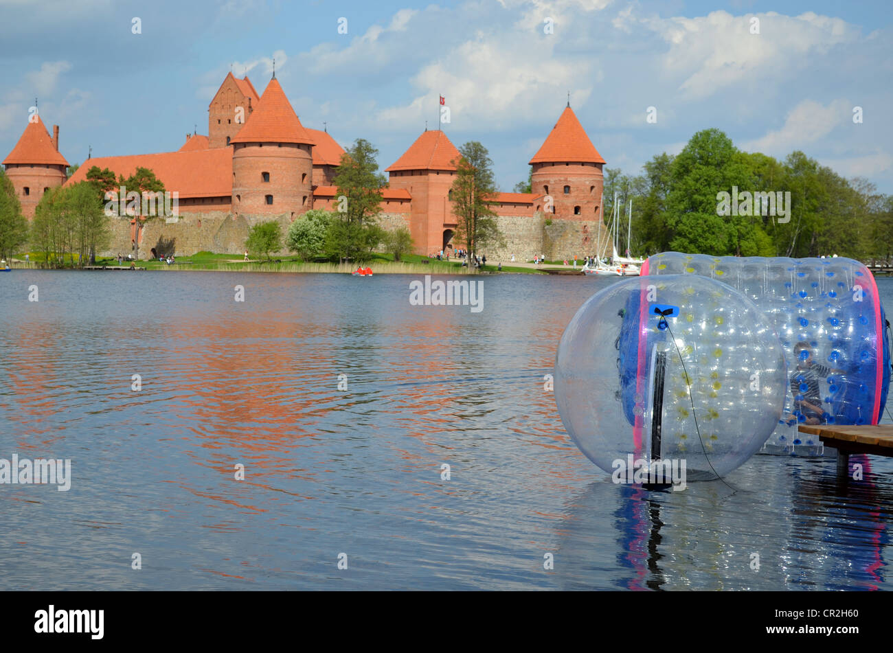 Zorbing air bubbles on water. Trakai Castle surrounded by lake Galve. XIV - XV century architecture in Lithuania. Stock Photo