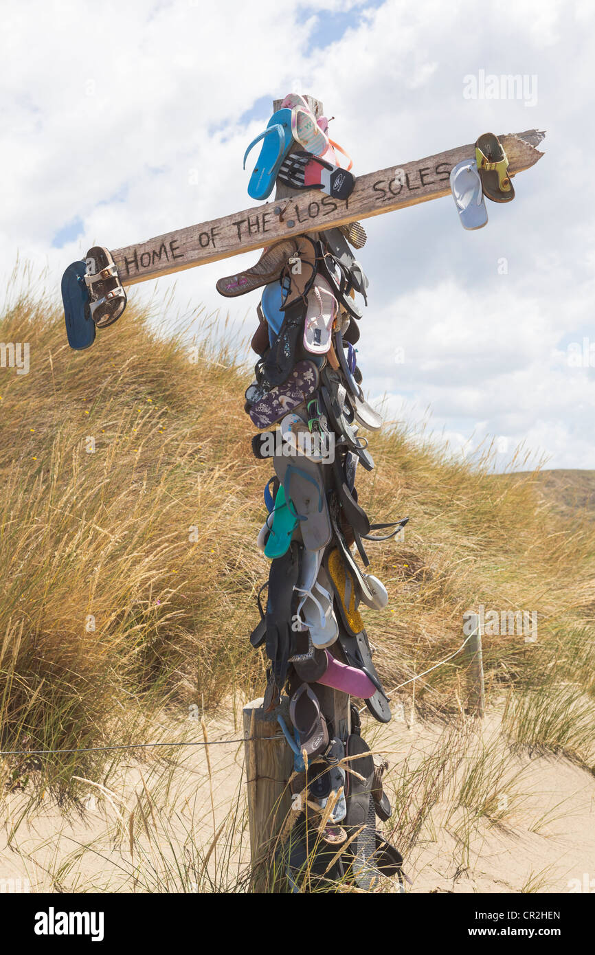 A pole with many sandals and the text 'Home of the lost soles' at Castlepoint, Wellington, New Zealand, Oceania Stock Photo