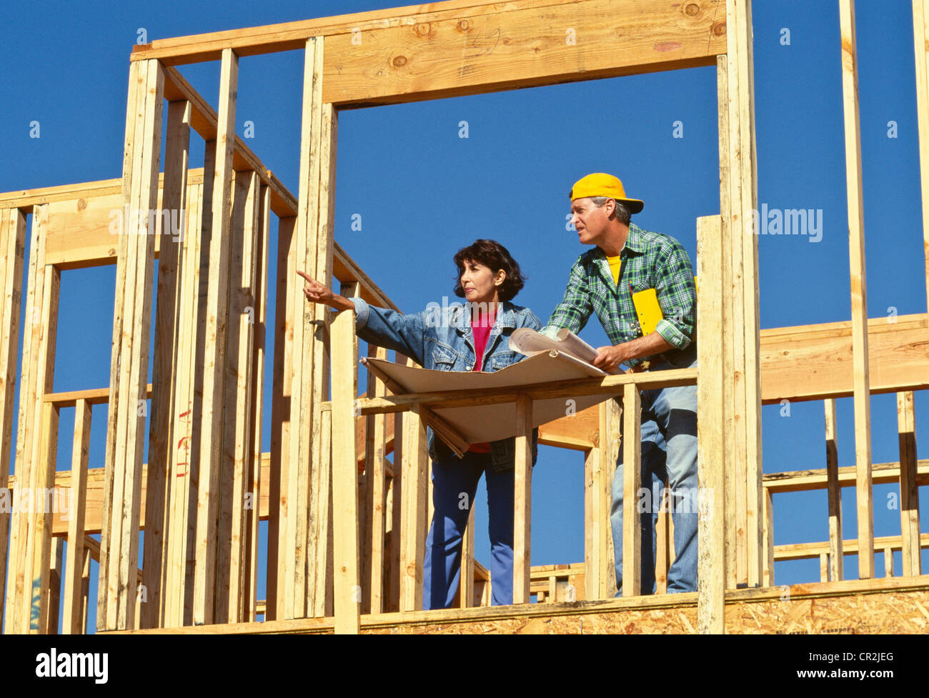 Female boss points to male worker (tradesman,) at construction site Stock Photo