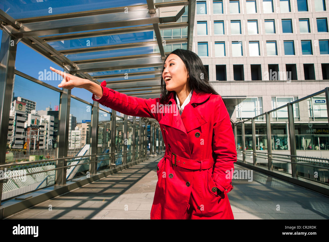 Woman in red coat pointing at city sights Stock Photo