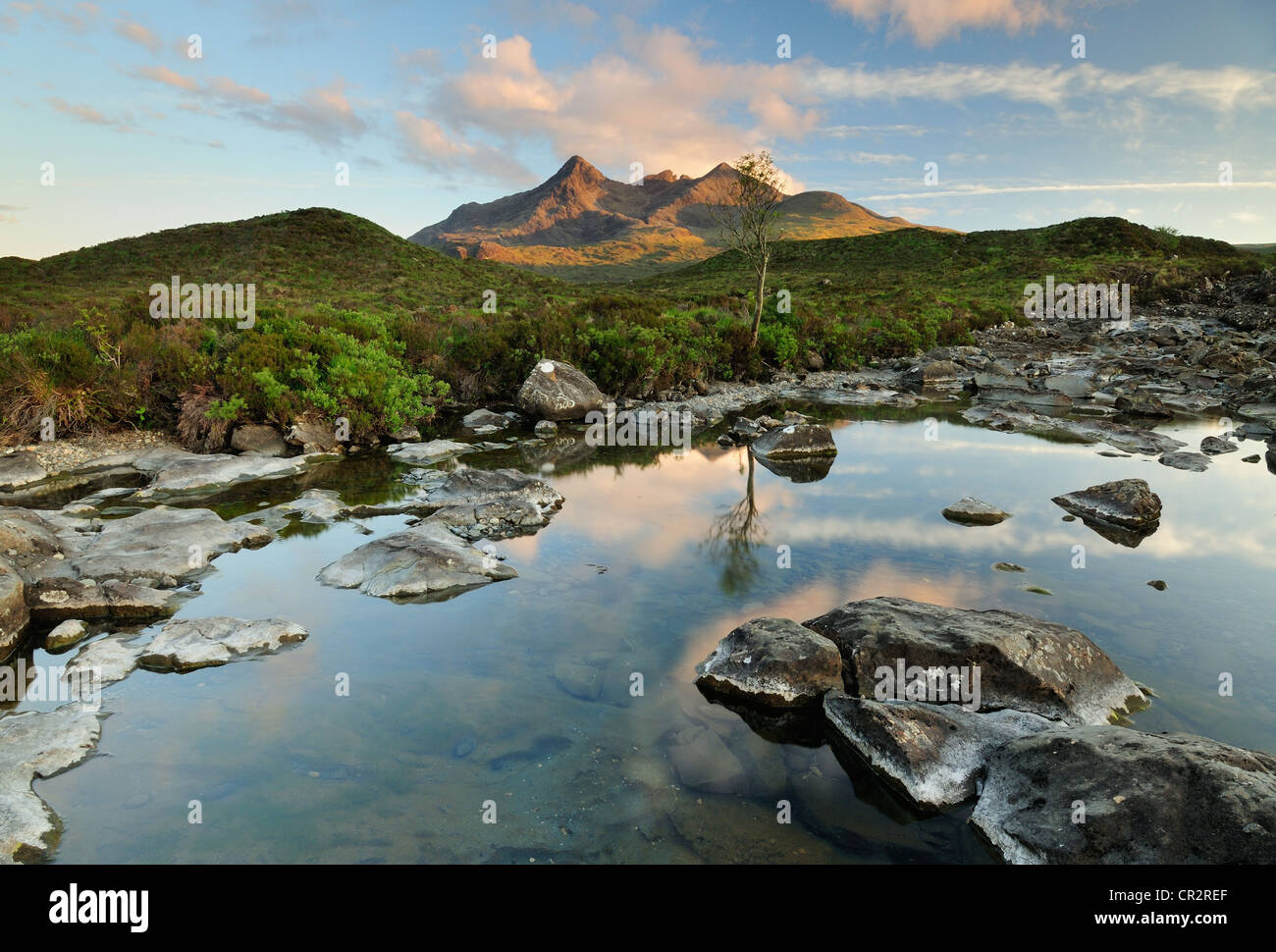Calm pools on the Allt Dearg Mor on the Isle of Skye with the sunlit peaks of the Black Cuillin hills in the background Stock Photo