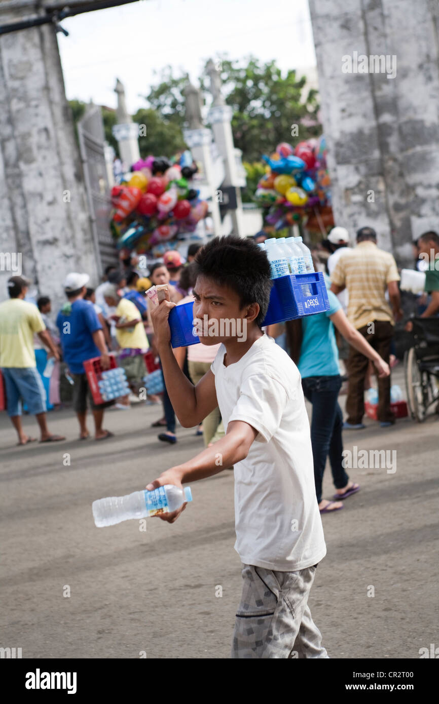 Filipino boy selling water outside Basilica of Santo Nino church. Cebu City, Cebu, Visayas, Philippines. Stock Photo