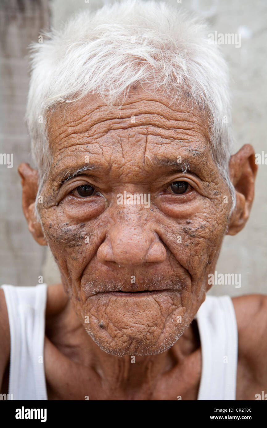 An old Filipino man sitting outside his home. Lapu-Lapu City, Metro Cebu, Mactan Island, Visayas, Philippines. Stock Photo