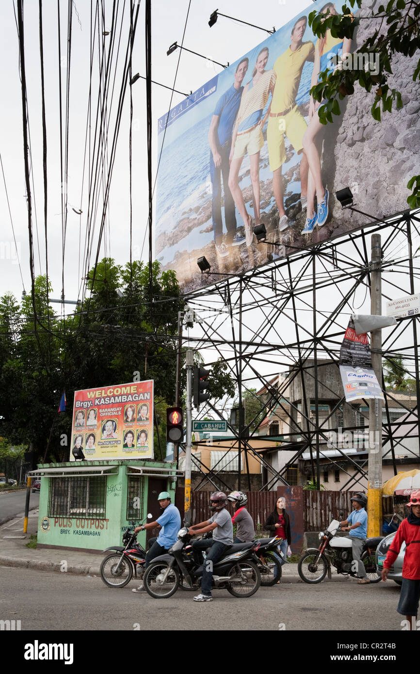 Motorcycles driving past advertising billboards. Cebu City, Cebu, Visayas, Philippines. Stock Photo