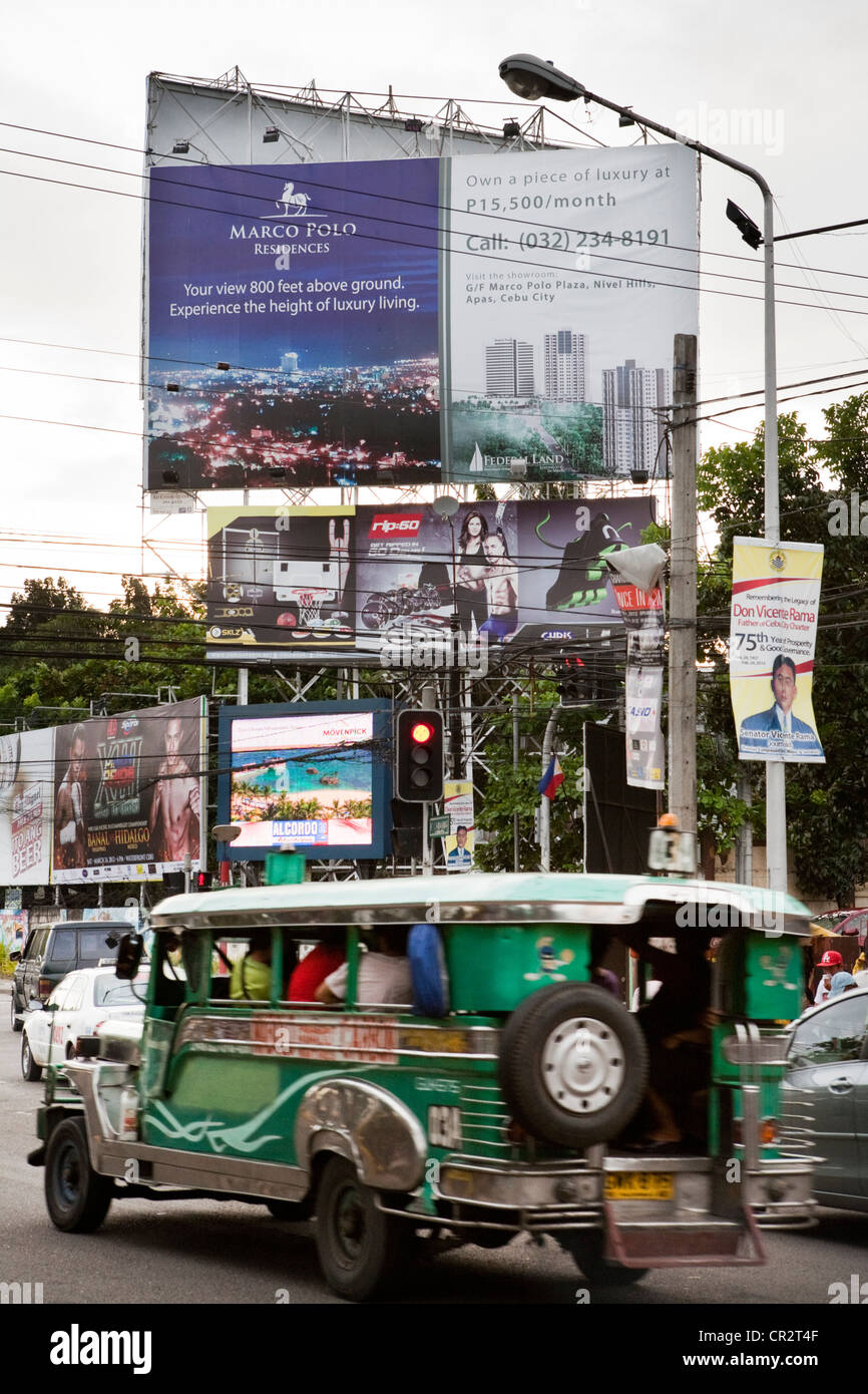 Jeepney driving past advertising billboards. Cebu City, Cebu, Visayas, Philippines. Stock Photo