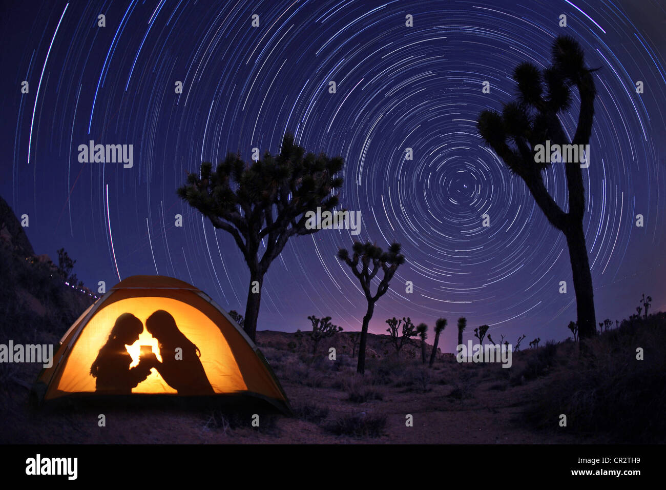 Children Camping at Night in a Tent With Star Trails Stock Photo