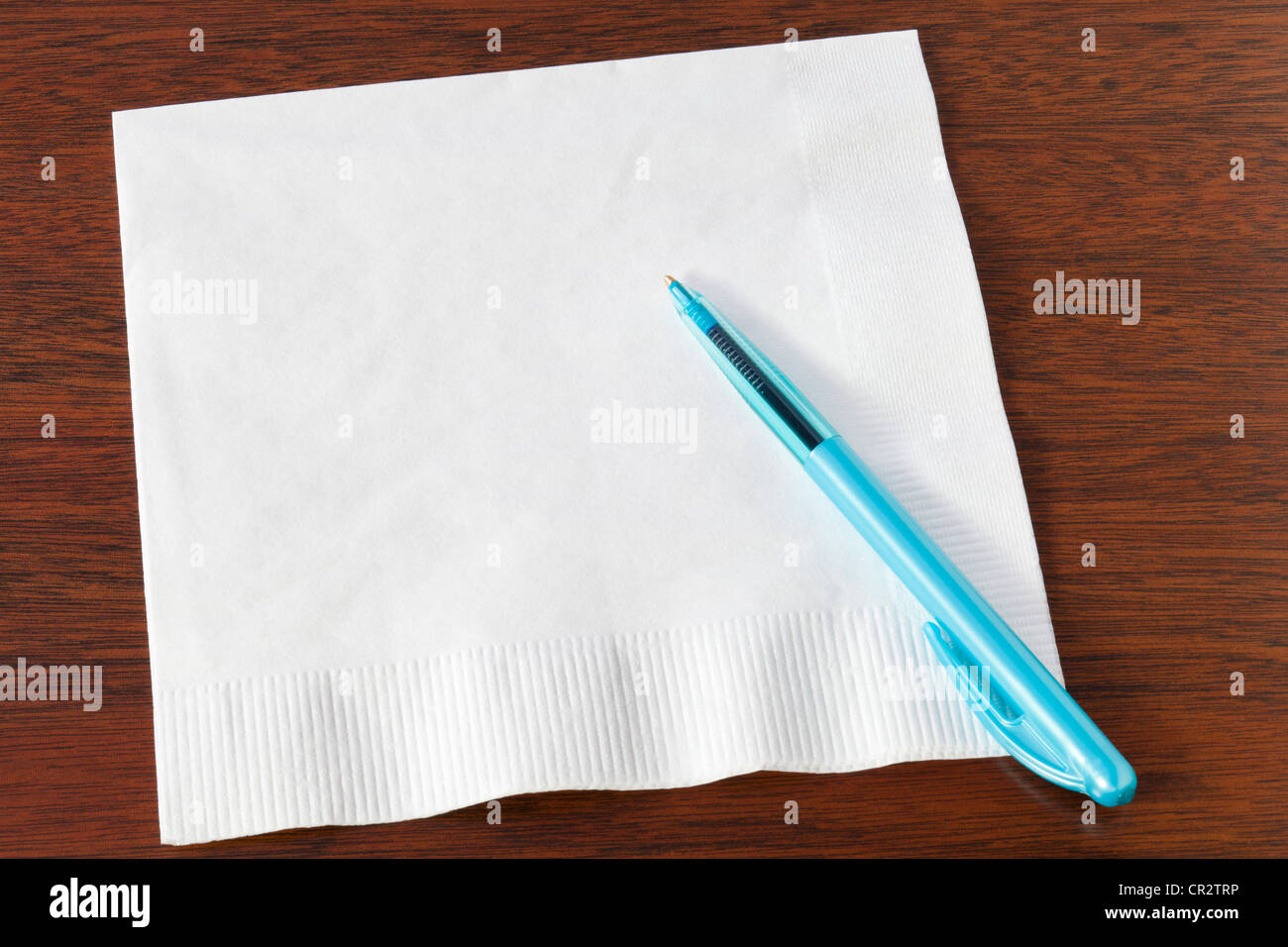 White napkin or serviette with turquoise biro on dark oak background. Ideal for your phone numbers and great ideas. Stock Photo