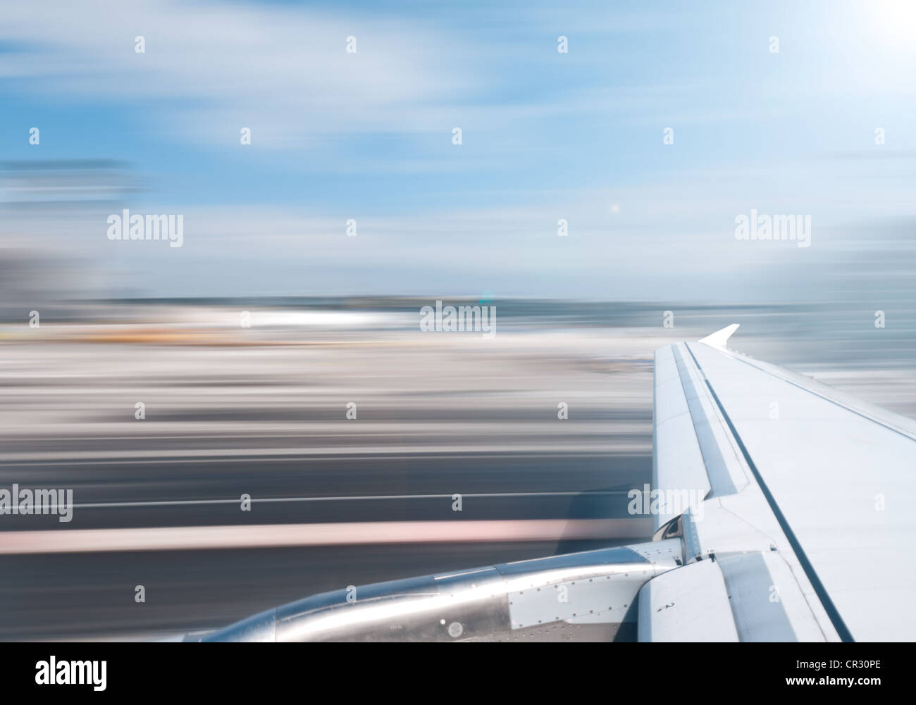 View of air plane wing during take off or landing. Motion blur of airport grounds and sky. Stock Photo