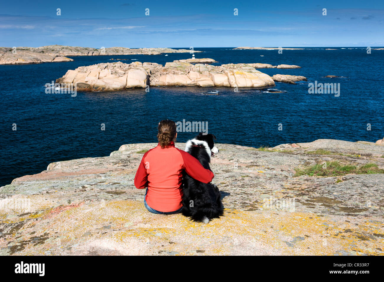 Girls with a Border Collie looking over the archipelago on the coast of Smoegen, Sweden, Scandinavia, Europe Stock Photo