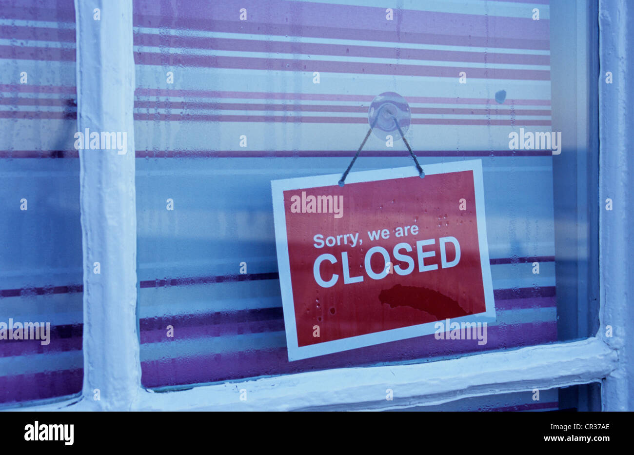 Detail of shop or cafe window with red and white striped blind drawn and sign stating Sorry We Are Closed Stock Photo