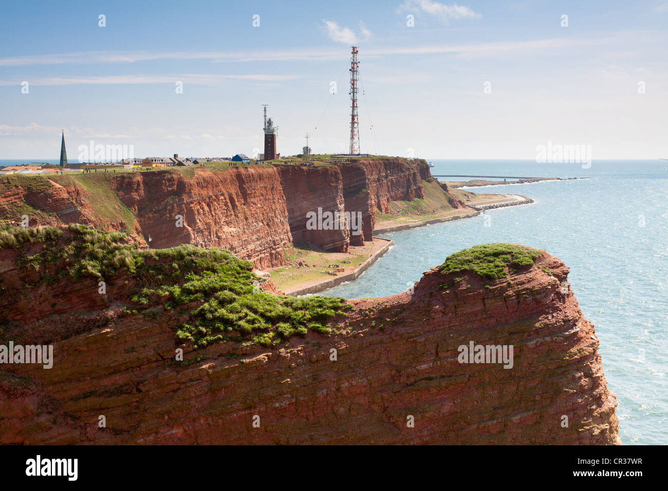 The prominent steep red sandstone cliffs of Heligoland with its lighthouse and a radio tower, Helgoland, Schleswig-Holstein Stock Photo