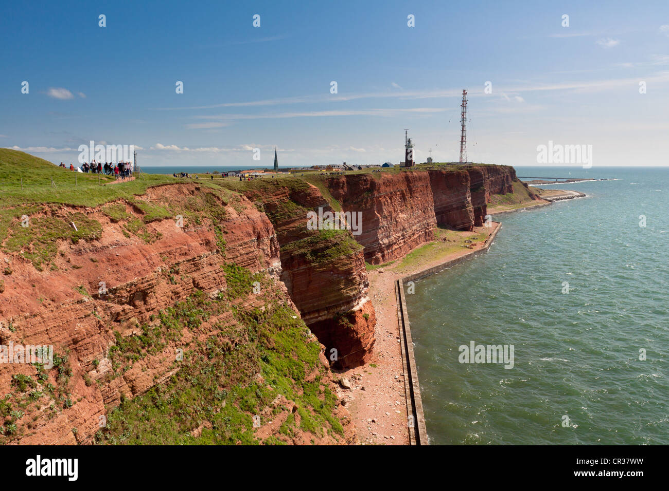 The prominent steep red sandstone cliffs of Heligoland with its lighthouse and a radio tower, Helgoland, Schleswig-Holstein Stock Photo