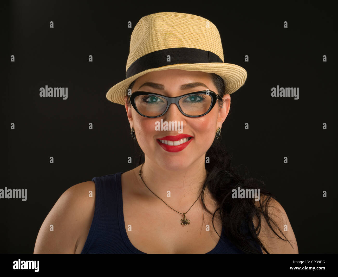 Young Mexican American Woman wearing glasses a panama style straw hat with black ribbon and red lipstick Stock Photo