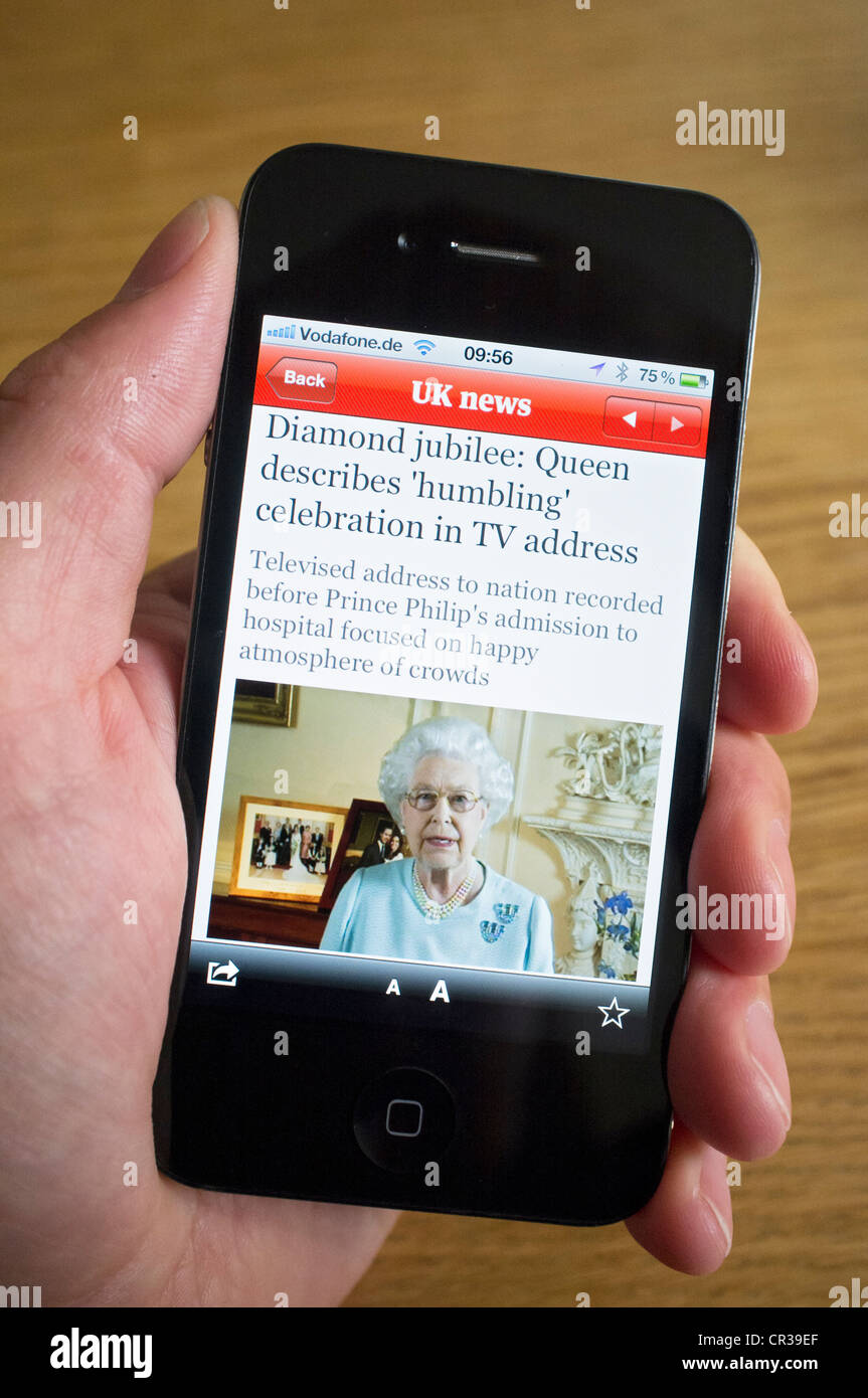 reading story about Queen's Diamond Jubilee using online newspaper App on an iPhone smartphone Stock Photo