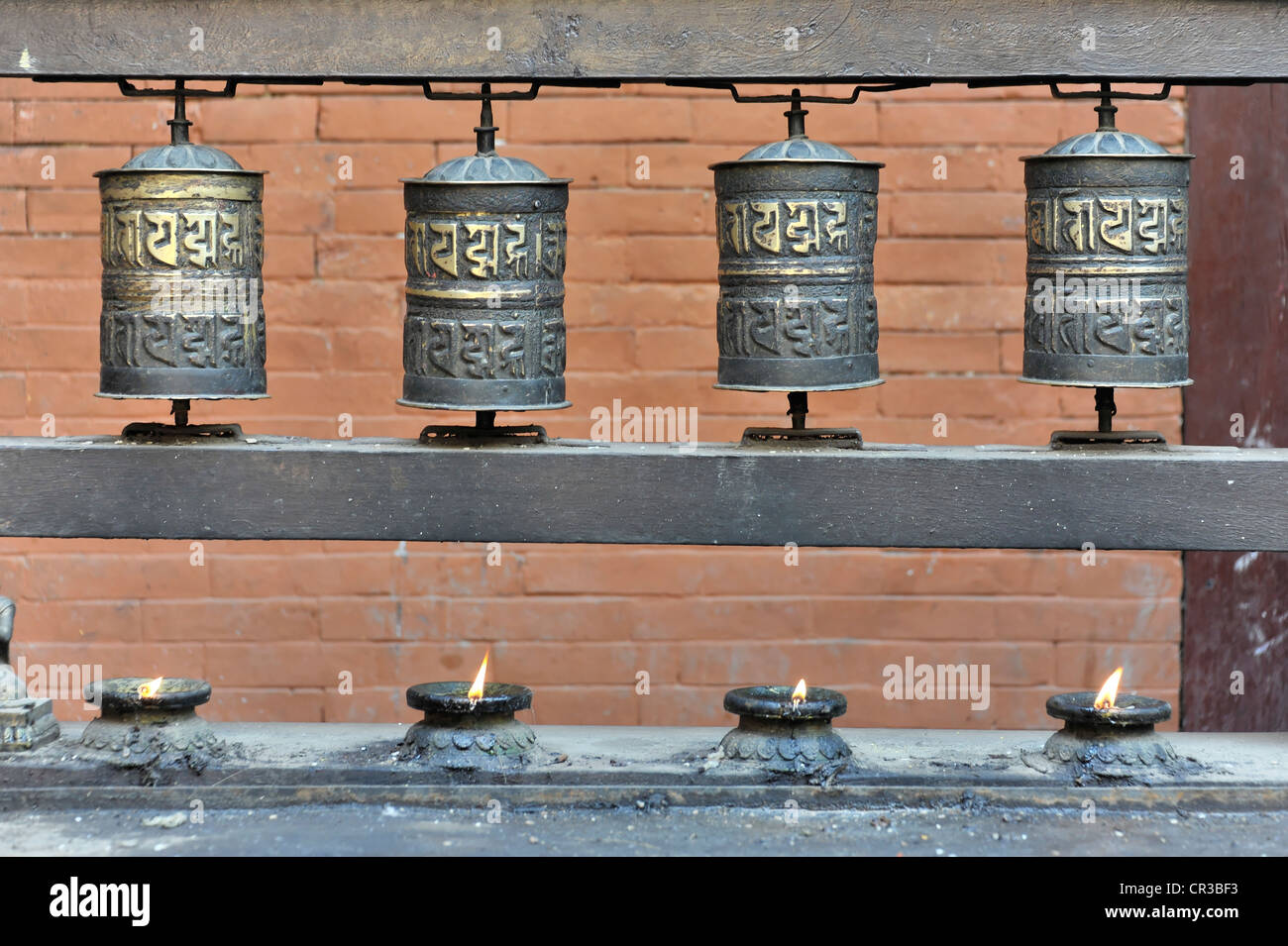 A row of butter lamps and prayer wheels at the Golden Temple, a buddhist temple in Patan, Nepal, Asia Stock Photo