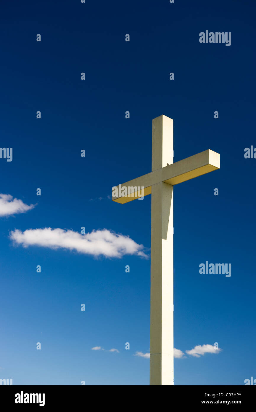 Cross against a blue sky with cumulus clouds Stock Photo