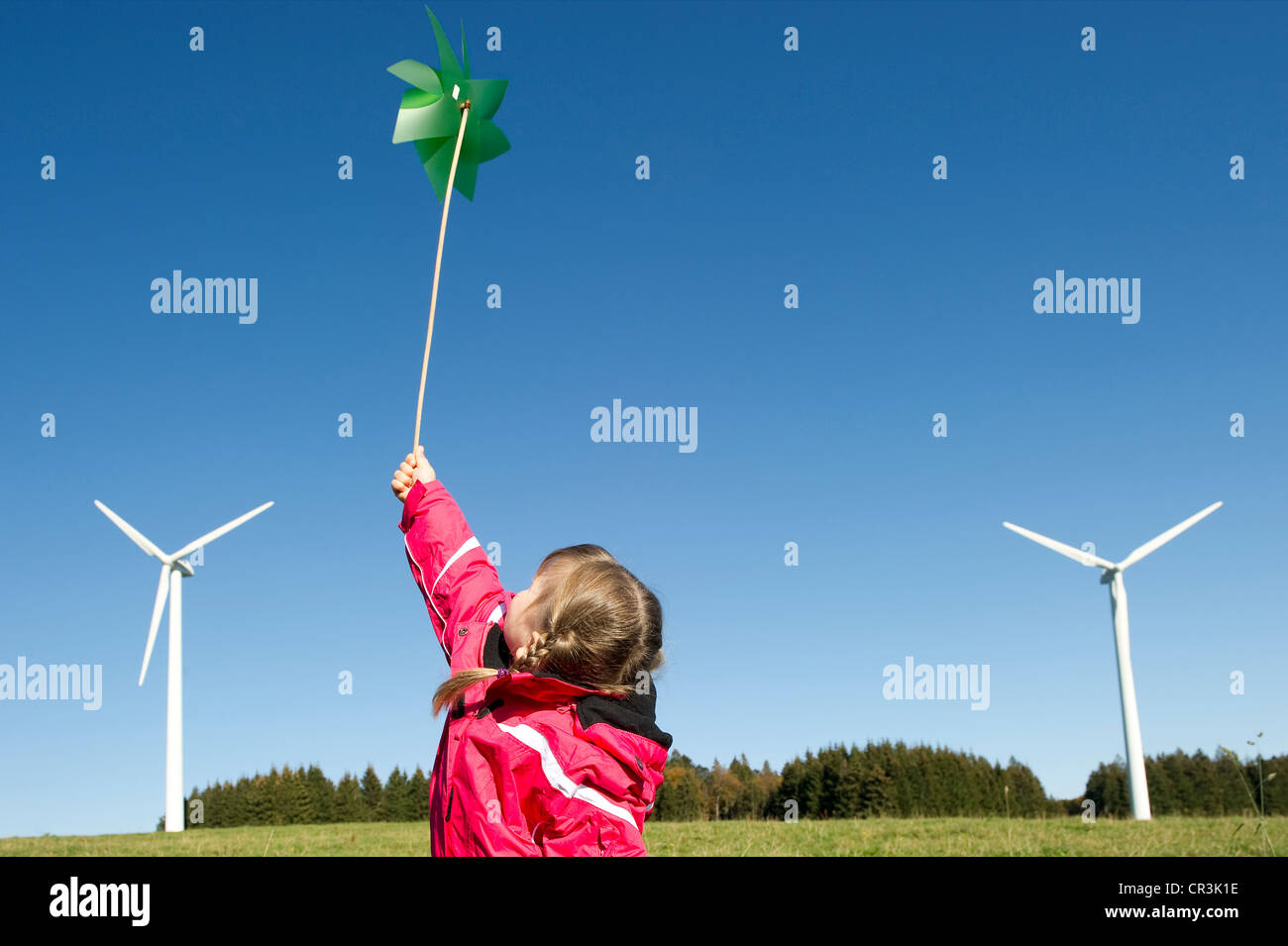 Girl holding a green pinwheel in front of wind turbines, near Freiburg in Breisgau, Black Forest, Baden-Wuerttemberg Stock Photo