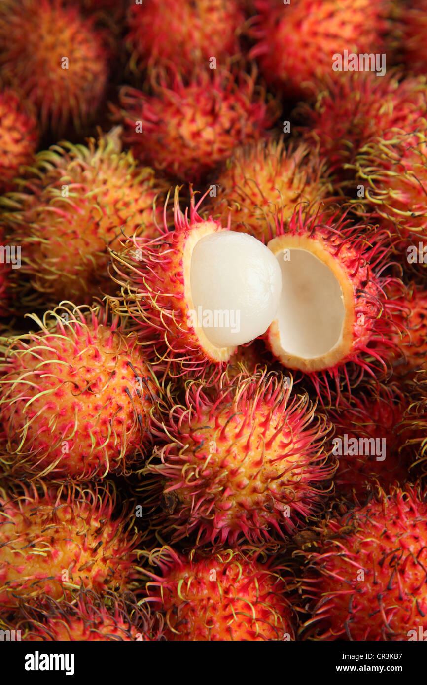 Rambutan background with one fruit cut open Stock Photo