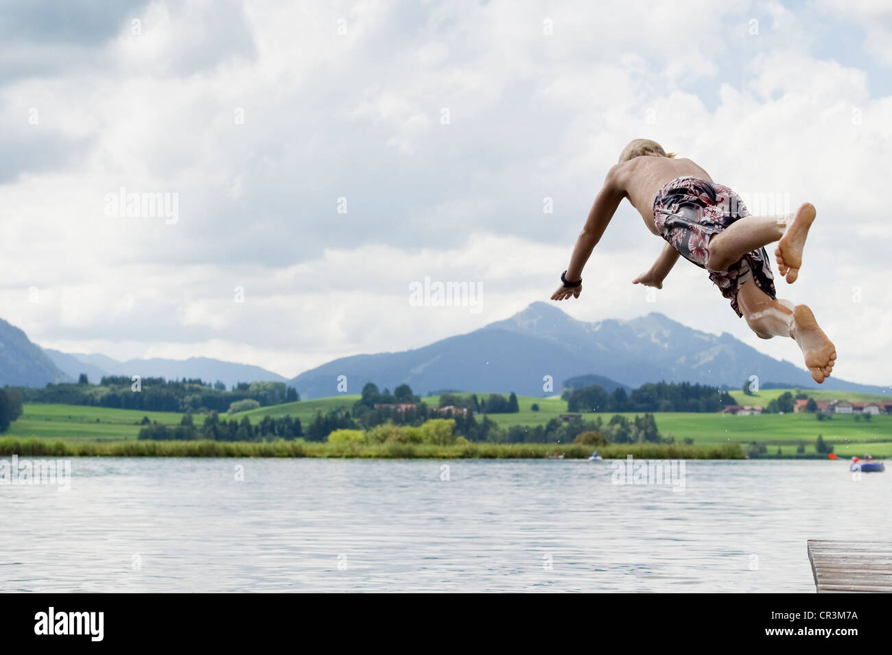 Boy jumping into Lake Hopfensee near Fuessen, Allgaeu, Bavaria, Germany, Europe Stock Photo