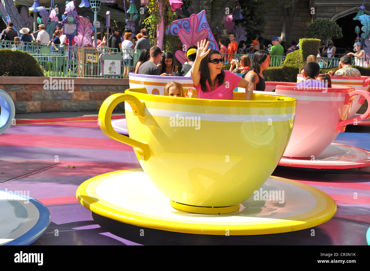 Families having fun waving while on Disneyland's Tea Cups and Saucers