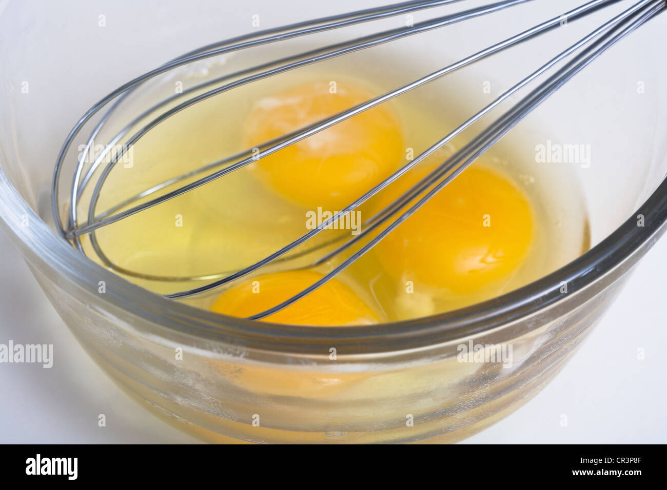 Three eggs in a bowl with an egg beater Stock Photo