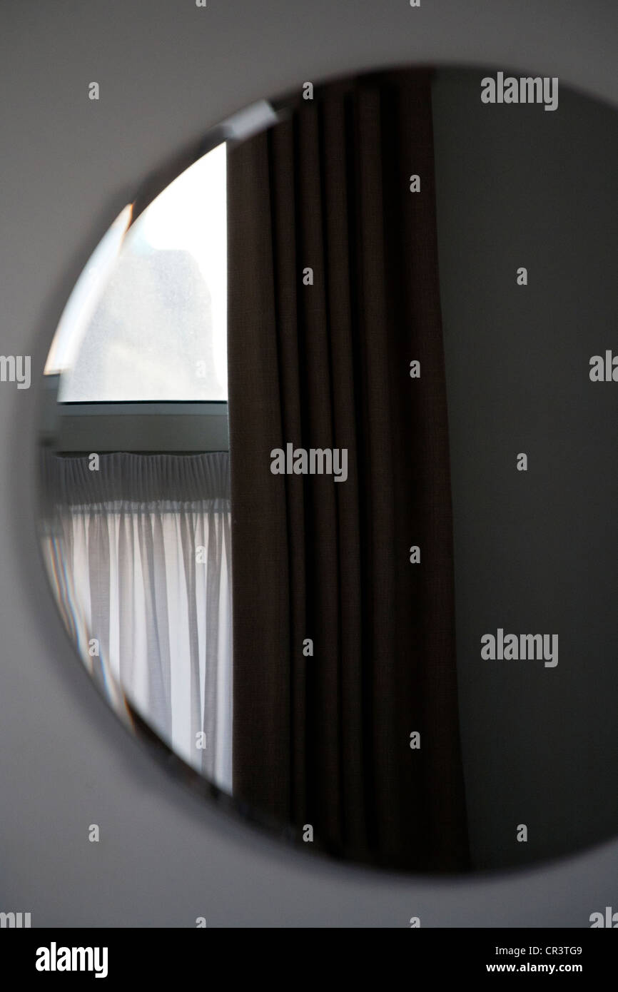 Curtain and window reflected in a round mirror on a hotel room wall, Great Victoria Hotel Bradford England UK Stock Photo