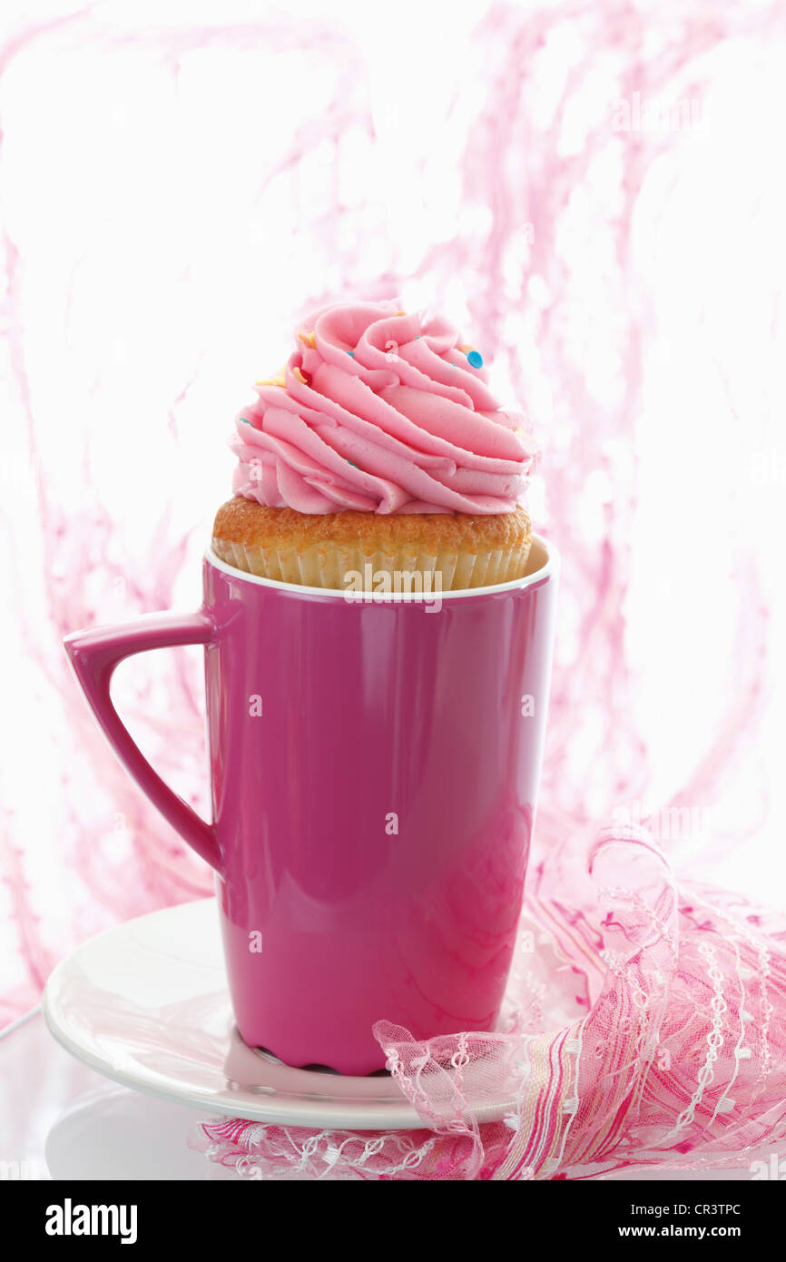 Cupcake with strawberry butter cream in pink coffee mug Stock Photo