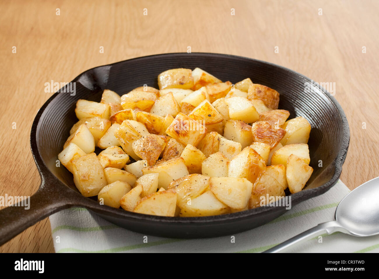 A small cast iron skillet or frying pan filled with home fries or saute potatoes. Stock Photo