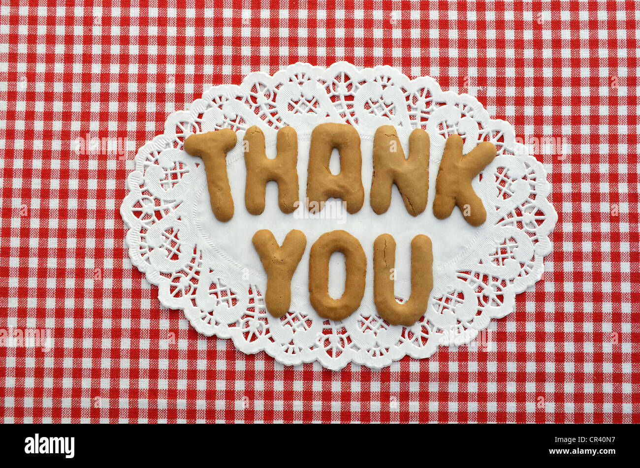 Thank you, written in alphabet biscuits on paper doily Stock Photo
