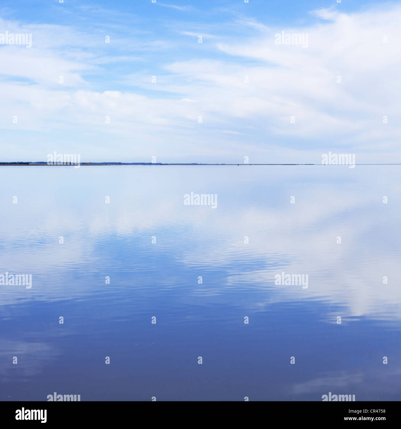 Smooth and tranquil water reflecting clouds. Stock Photo