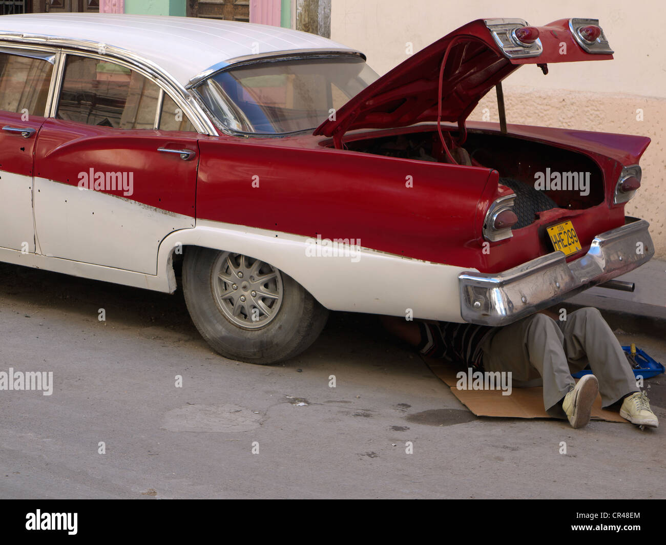 Cuban repairing an American vintage car while lying under his car, Havana, Cuba, Latin America Stock Photo