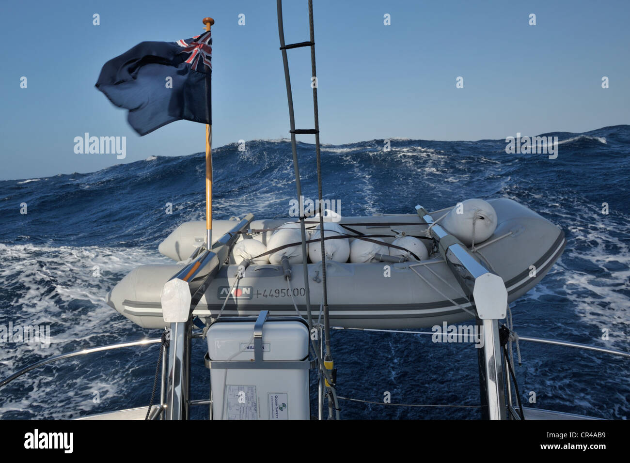 Large waves seen over a dinghy on the davits of a cruising yacht, an