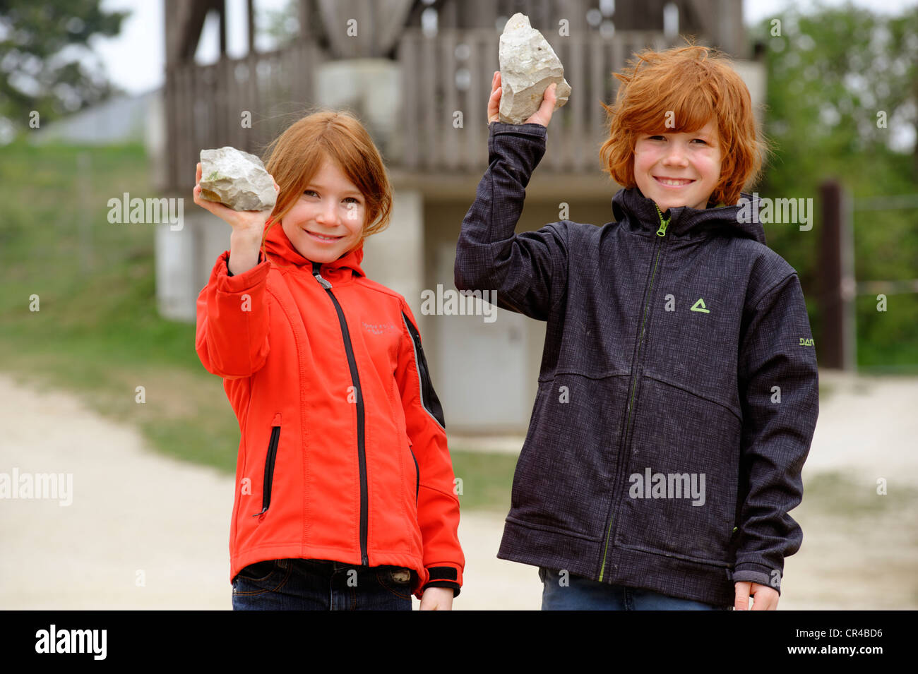 Two children holding up stones containing fossils from breaking rocks at Geozentrum Hohenmirsberger Platte, geo-centre Stock Photo