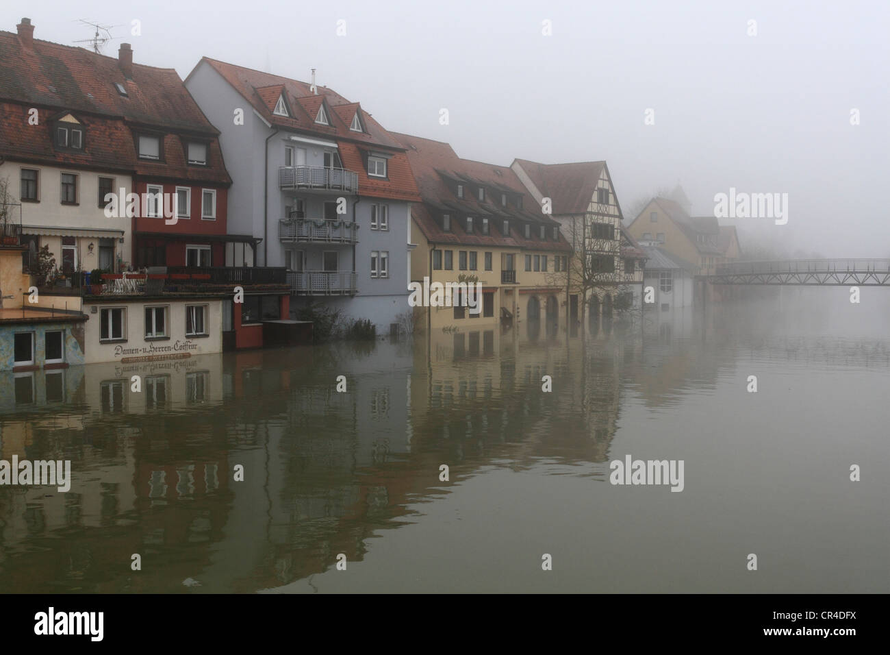 Floodwaters and fog, buildings on the bank of the Tauber river, seen from the Tauber river bridge on Bahnhofstrasse street from Stock Photo