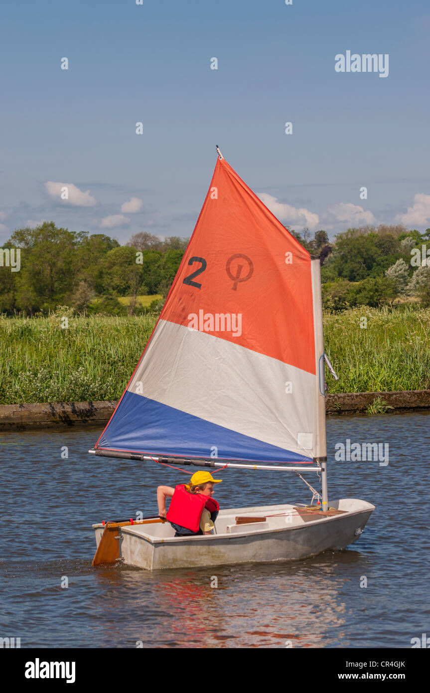 An eight year old boy sailing in an optimist dinghy boat in the Uk Stock Photo