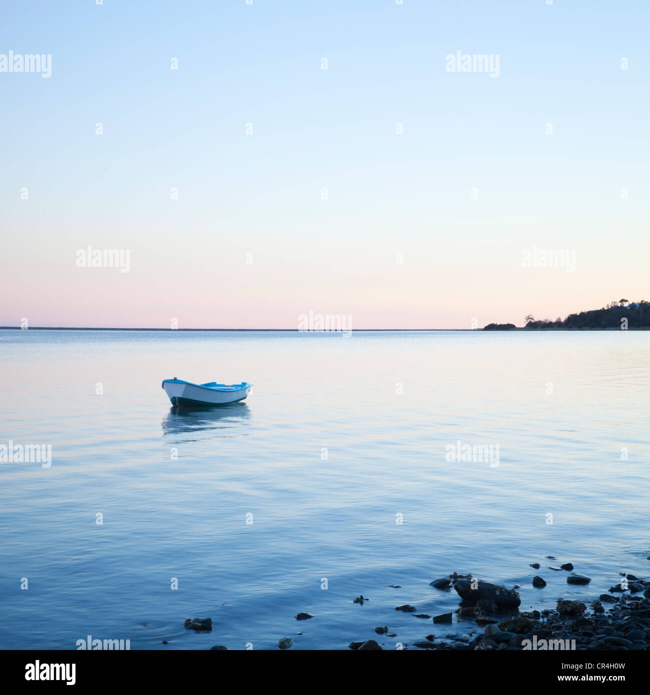 Small rowing boat anchored on gently lapping water Stock Photo