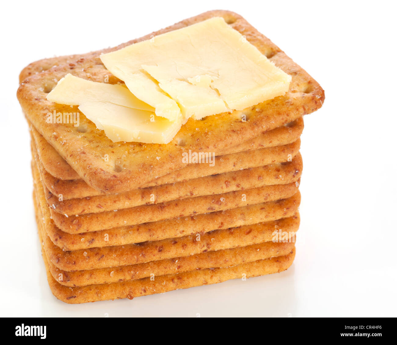 Crumbly aged cheddar on a stack of crackers, on a reflective white plate. Stock Photo