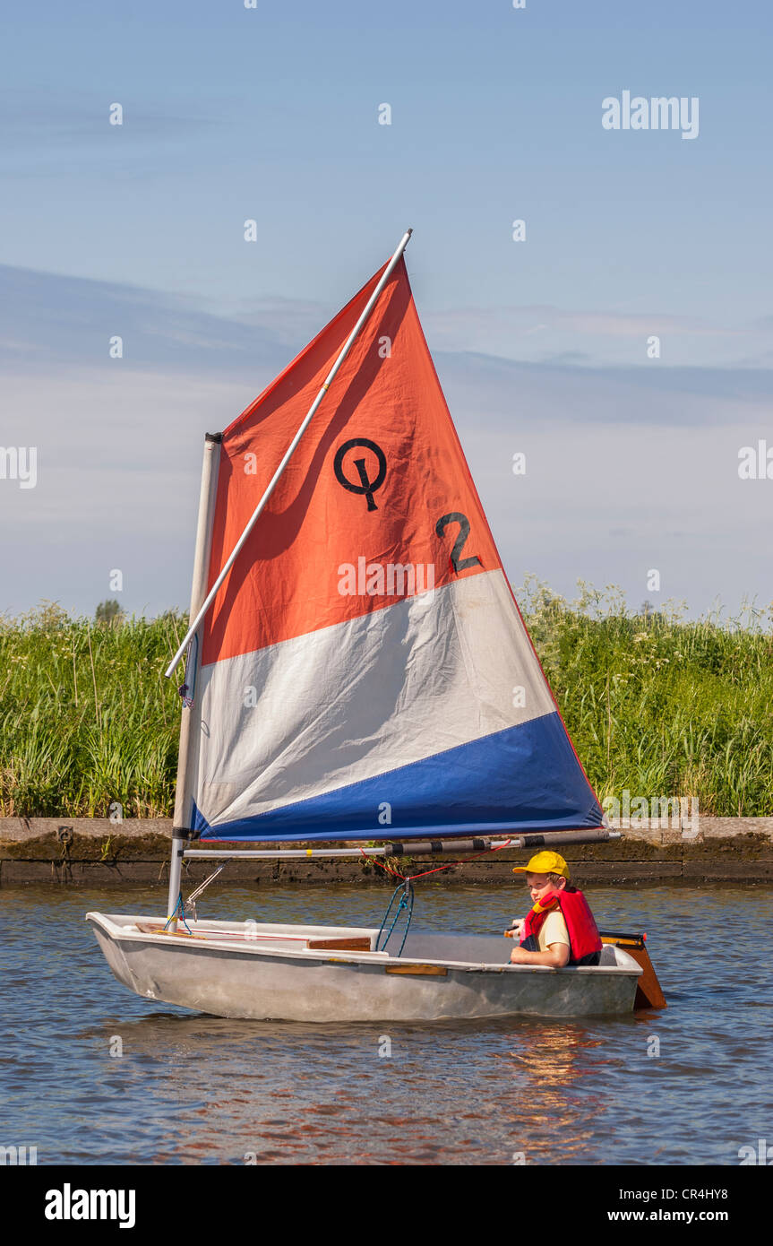 An eight year old boy sailing in an optimist dinghy boat in the Uk Stock Photo