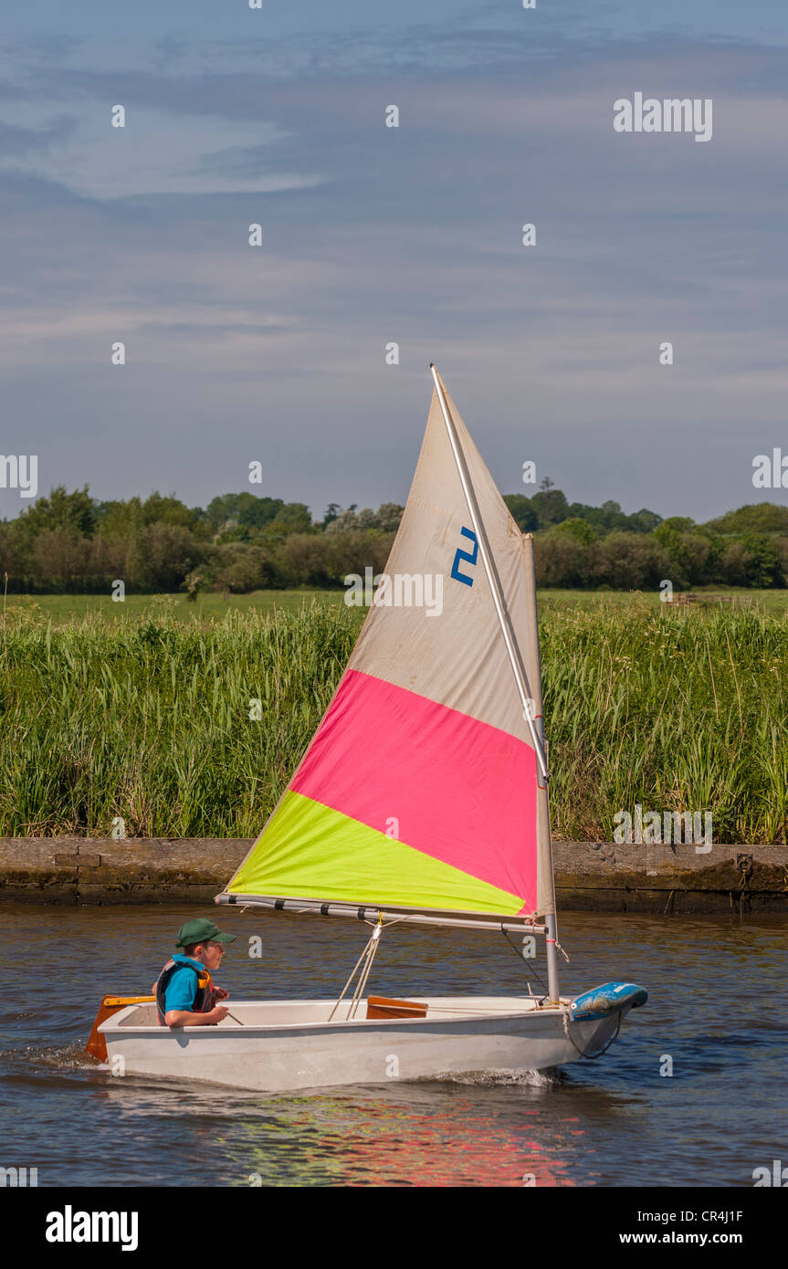 A twelve year old boy sailing in an optimist dinghy boat in the Uk Stock Photo