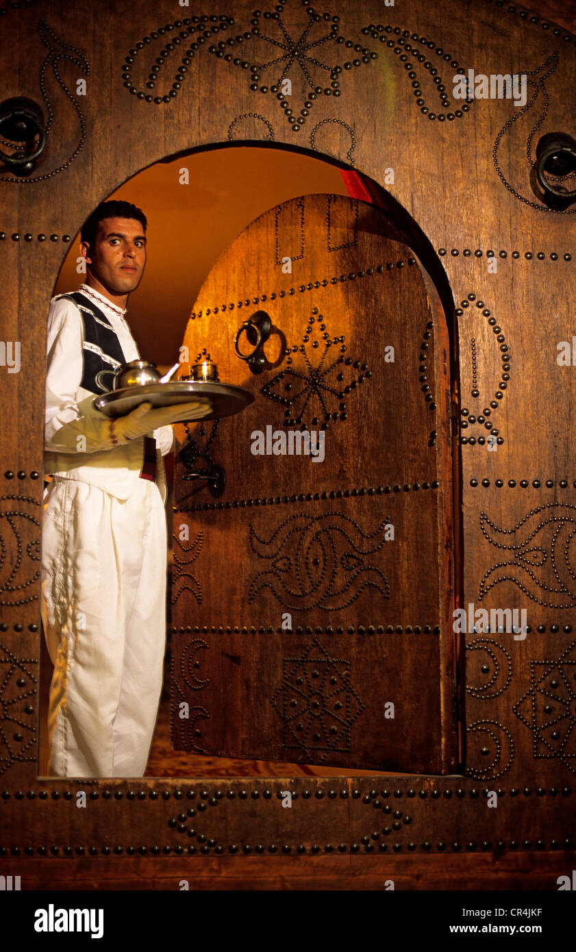 Tunisia, Tozeur Governorate, Tozeur, Tamerza Palace luxury hotel, waiter with a tea tray passing through a carved door Stock Photo
