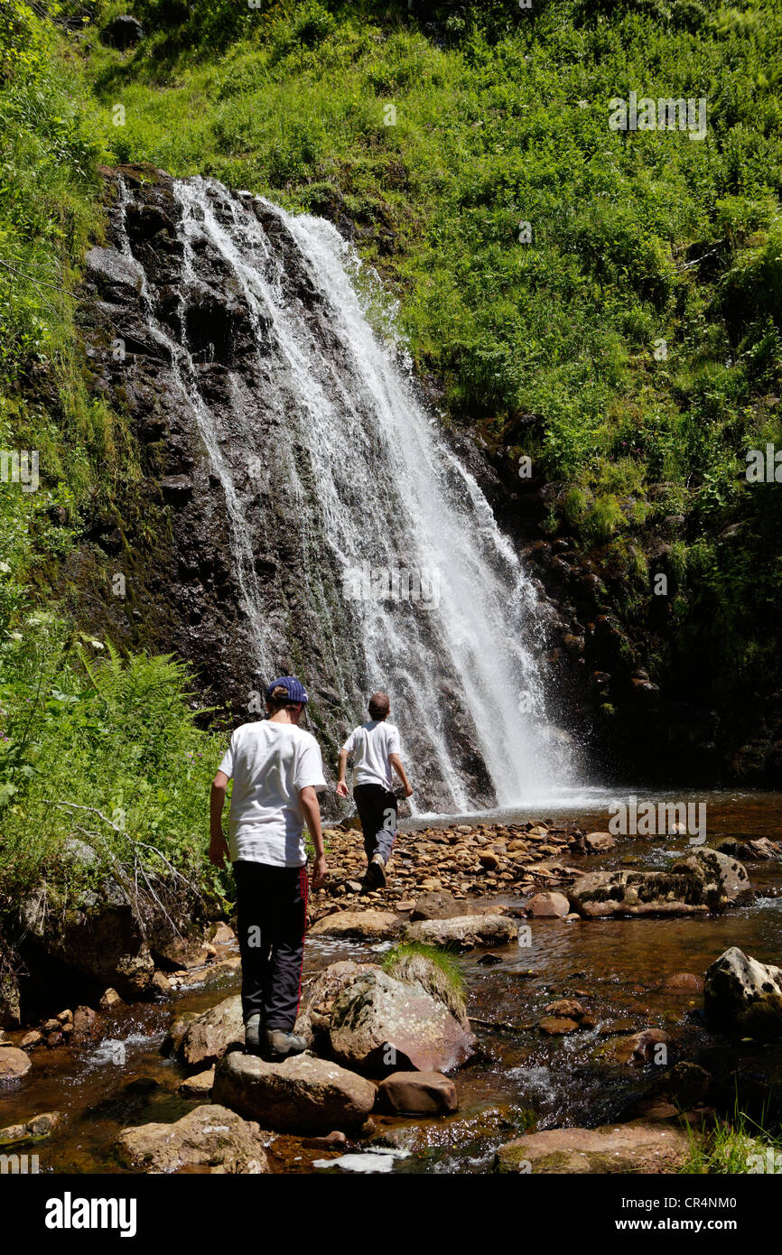 Hikers at waterfall, Fontaine Salee reserve, Auvergne Volcanoes Regional Nature Park, massif of Sancy, Puy de Dome, France Stock Photo