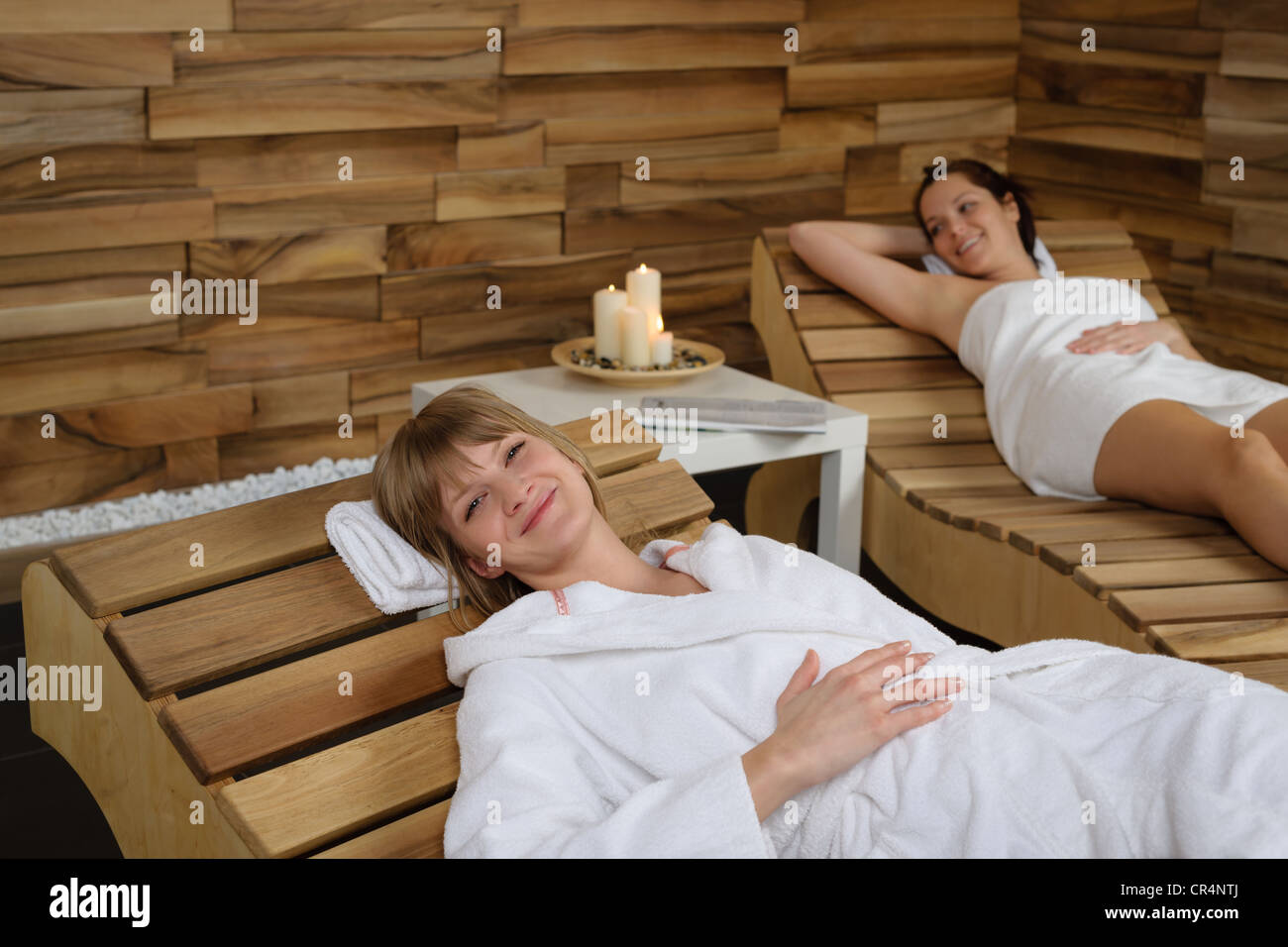Happy young woman relaxing on wooden chair at wellness center Stock Photo