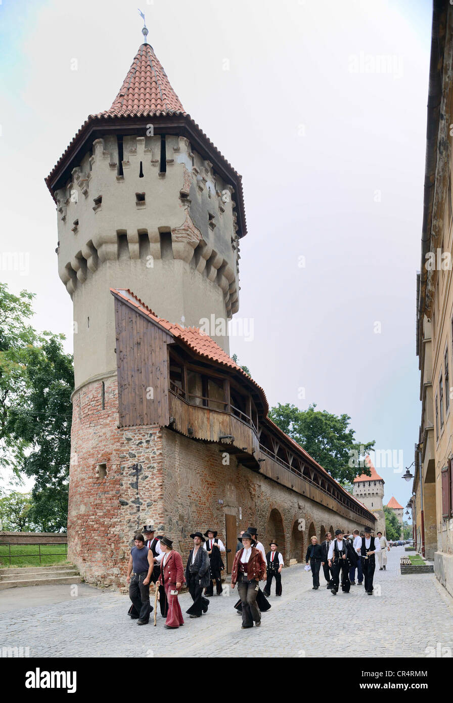 Travelling journeymen standing in front of defensive wall and tower of the craft guilds in Strada Cetatii, Sibiu, Romania Stock Photo
