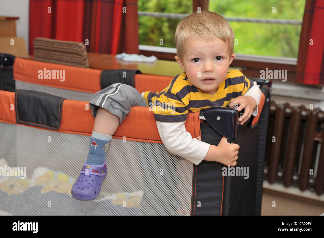 Little boy, 3 years, trying to climb out of a travel cot Stock Photo Alamy