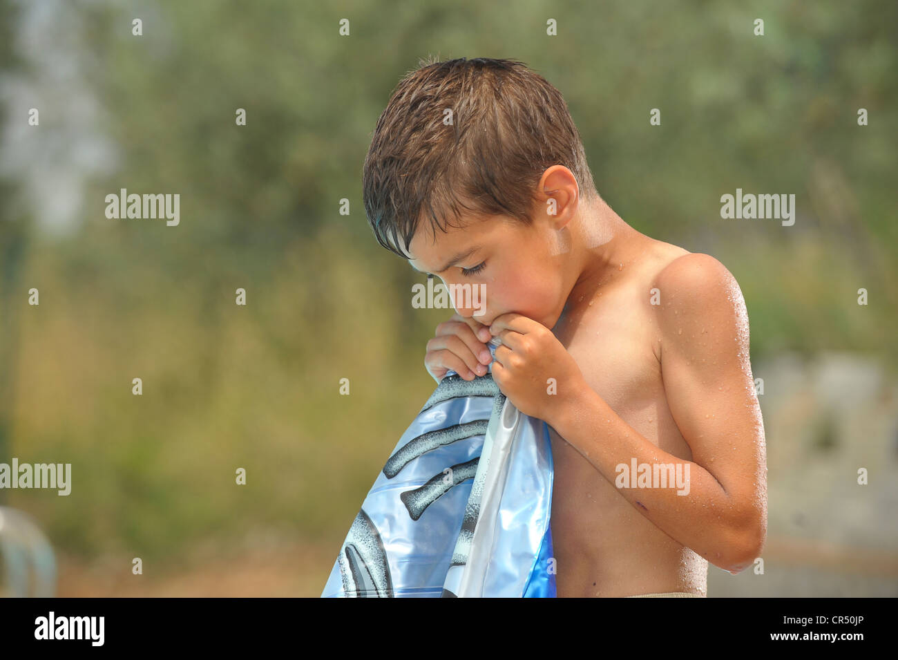 Boy, 8 years, inflating a floating mattress Stock Photo