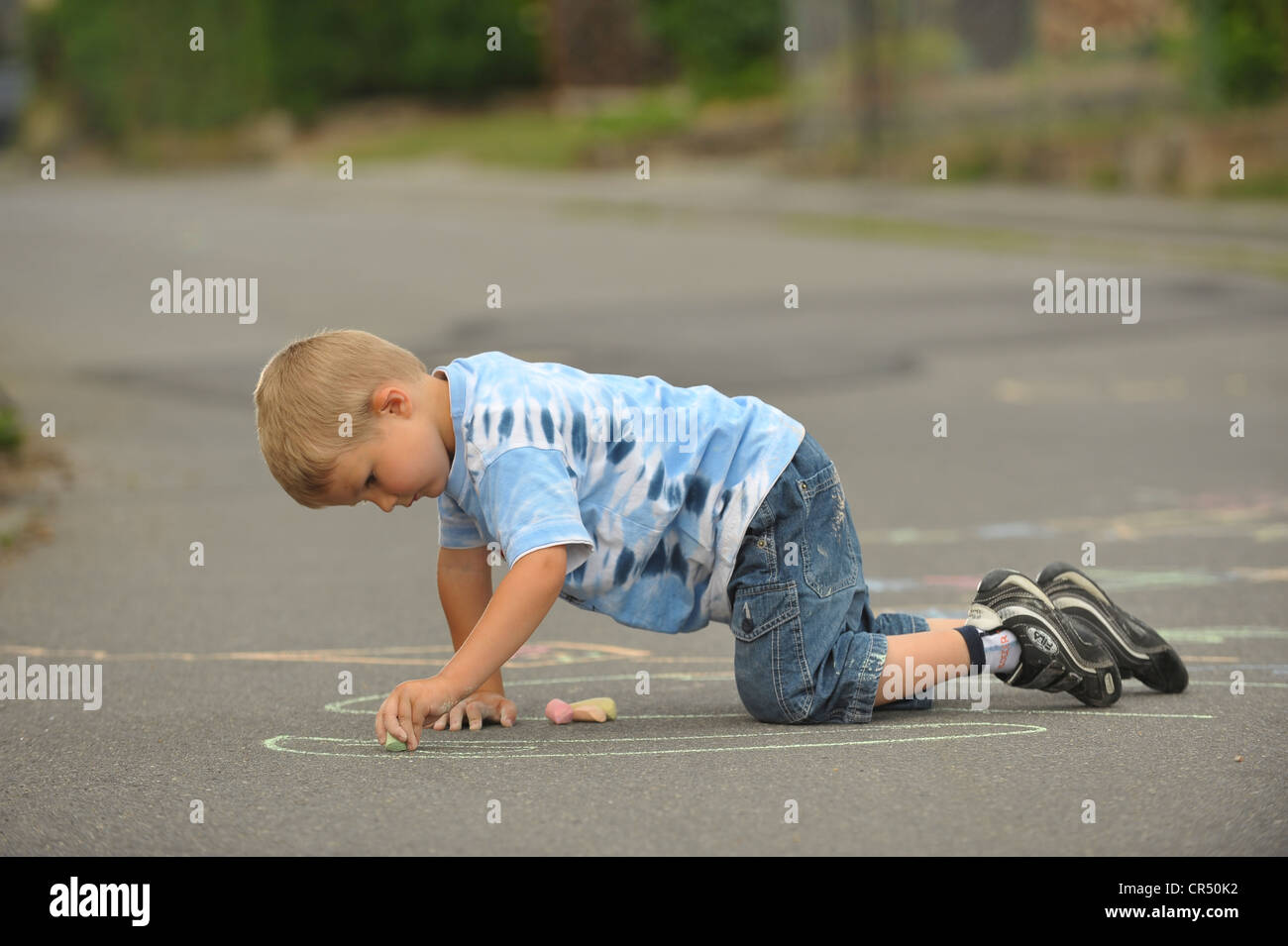 Boy, 4 years, painting with chalk on asphalt Stock Photo - Alamy