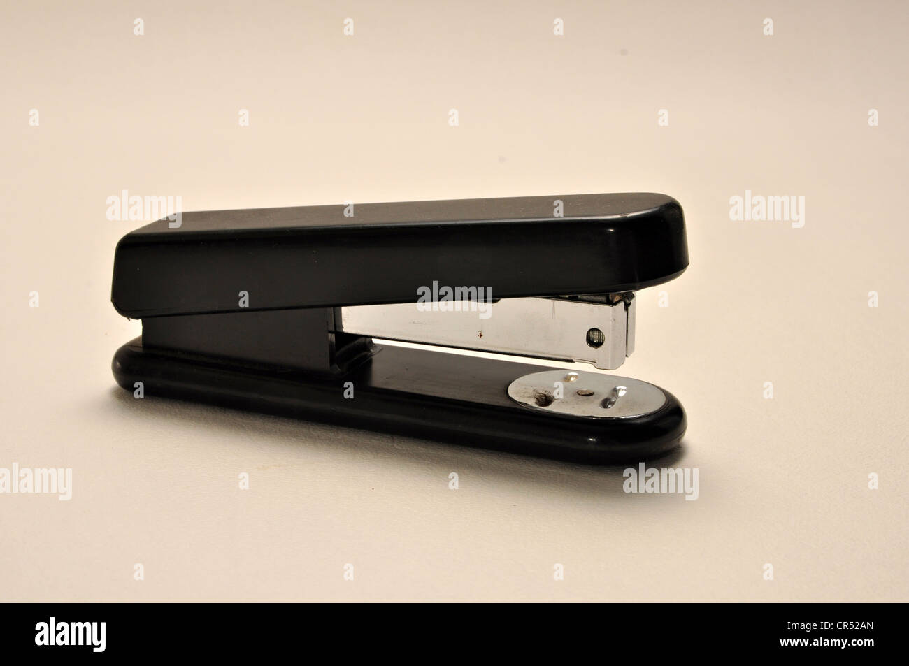 A black stapler is on a plain white background. Stock Photo