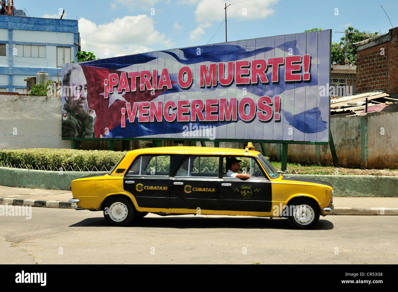 Stretched Lada taxi in front of an advertising panel with political propaganda on it, Fidel Castro, Socialismo o muerte Stock Photo