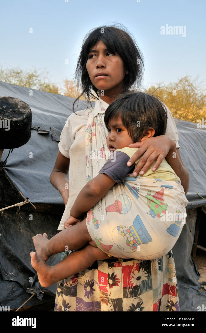 Young indigenous mother from the Wichi Indians tribe carrying a child, Zapota, Gran Chaco, Salta Argentina, South America Stock Photo
