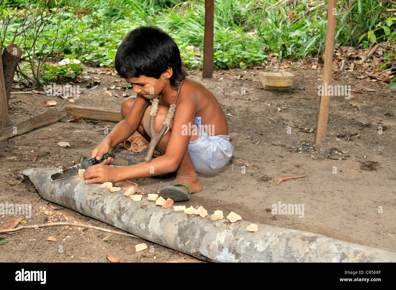 Boy cutting bricks so he can use them for his slingshot, Acampamento 12 de Otubro landless camp, Movimento dos Trabalhadores Stock Photo
